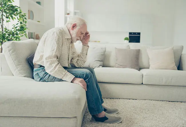 A senior man feeling dizzy and touching his head